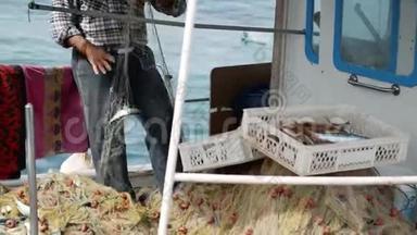 渔夫从渔网中捞出一条鱼。 土耳其博德鲁姆港的老年水手